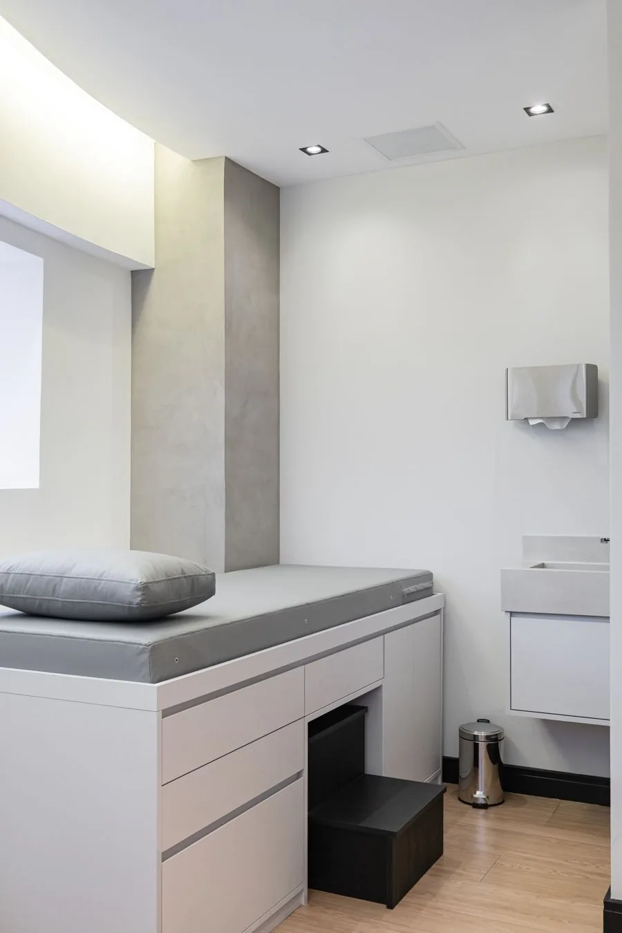 Sala de procedimentos com maca branca e bancada de apoio