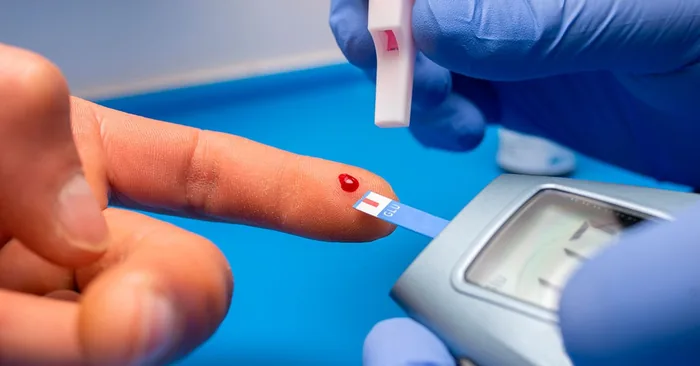 Teste de glicemia capilar sendo feito na ponta do dedo com glicosímetro