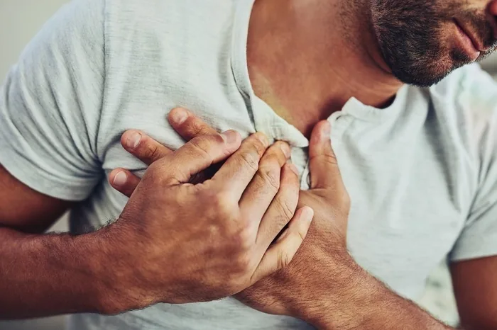 Homem com as duas mãos sobre o peito sentindo o coração acelerado