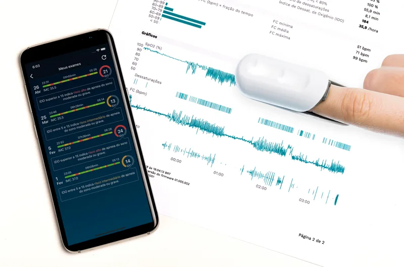 Sensor de sono no dedo ao lado do celular exibindo o gráfico da noite